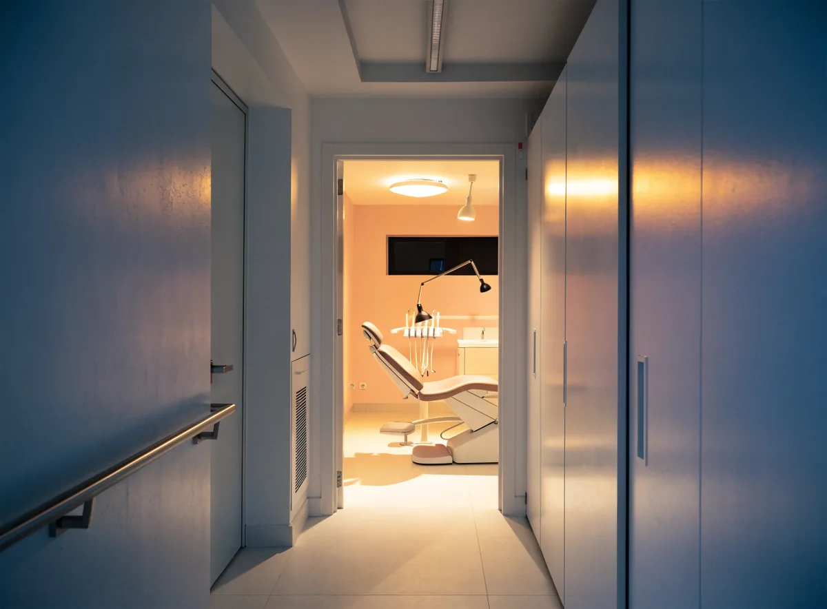 Clinic corridor with a lit treatment room at night (illustrative)