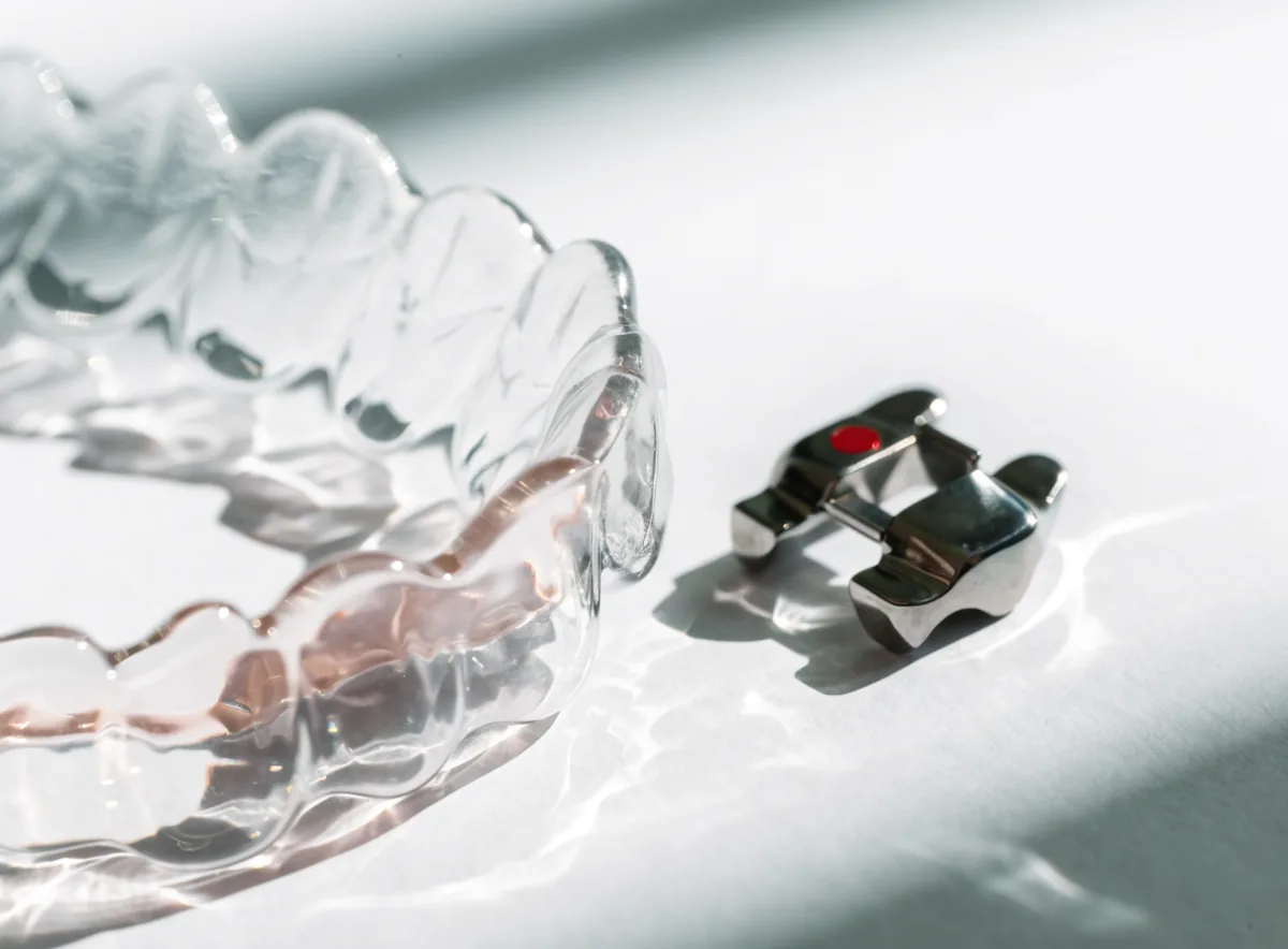 Clear aligner tray beside an orthodontic bracket (illustrative)